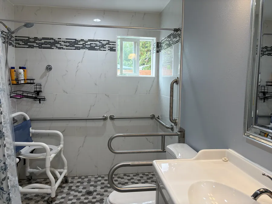 An accessible bathroom with a shower chair, grab bars and a step-free shower