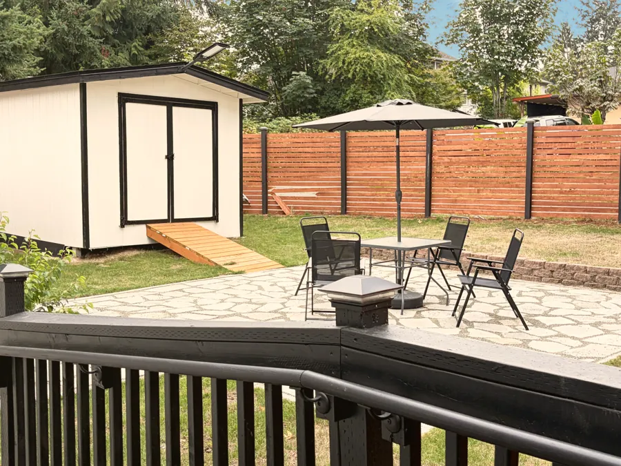 The back garden with a lawn, a shed and the patio seating