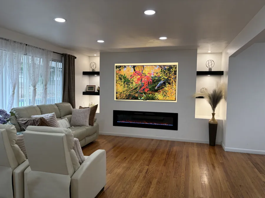 The living room with sofas and armchairs, a long fireplace and a lit picture of autumn trees