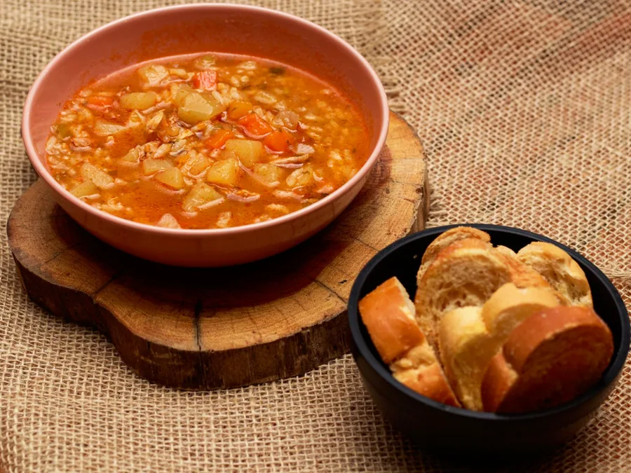 A bowl of vegetable soup served with bread