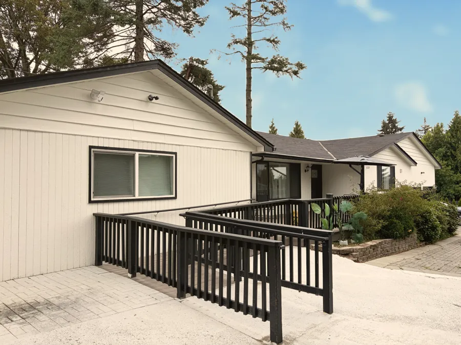 A wide wheelchair ramp with black railings leading to the front door